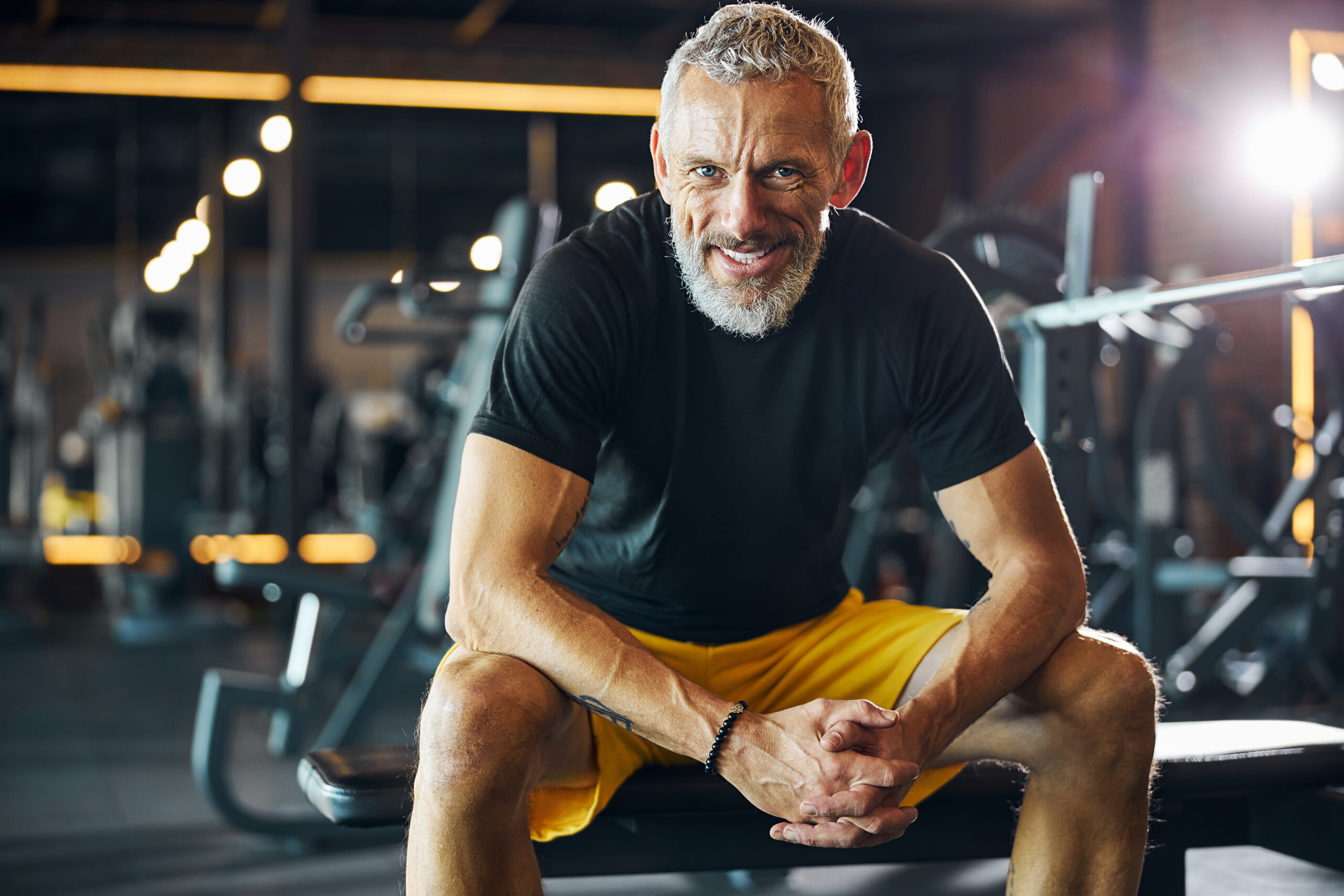 Sportsman with a happy smile sitting on the weight bench